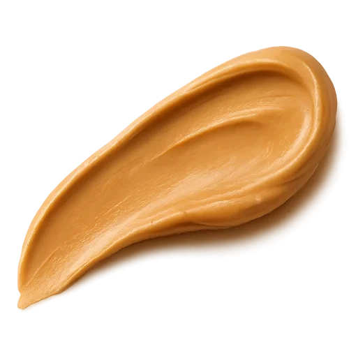 A smooth, appetizing peanut butter swash spread in an elegant curved stroke, rich golden-beige tones, creamy and glossy texture with natural highlights, appearing thick and luscious. The edges of the spread are soft and organic, as if lightly smoothed with a knife. Warm soft lighting to enhance depth and richness. Include a gentle, realistic shadow beneath the swash so it appears resting on the label surface. No background, no plate or surface — transparent PNG, photorealistic detail, premium artisanal food styling, refined and minimal, cozy warm visual mood.make the swash shape slightly dynamic and flowing, like a natural brush stroke, visually guiding the eye across the label.