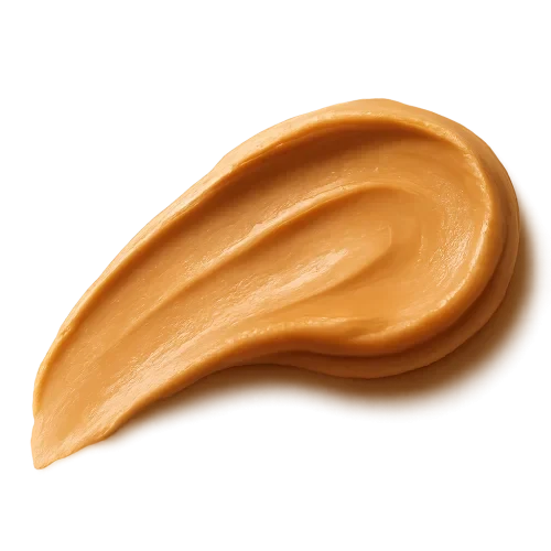 A smooth, appetizing peanut butter swash spread in an elegant curved stroke, rich golden-beige tones, creamy and glossy texture with natural highlights, appearing thick and luscious. The edges of the spread are soft and organic, as if lightly smoothed with a knife. Warm soft lighting to enhance depth and richness. Include a gentle, realistic shadow beneath the swash so it appears resting on the label surface. No background, no plate or surface — transparent PNG, photorealistic detail, premium artisanal food styling, refined and minimal, cozy warm visual mood.make the swash shape slightly dynamic and flowing, like a natural brush stroke, visually guiding the eye across the label.make it facing to the left.